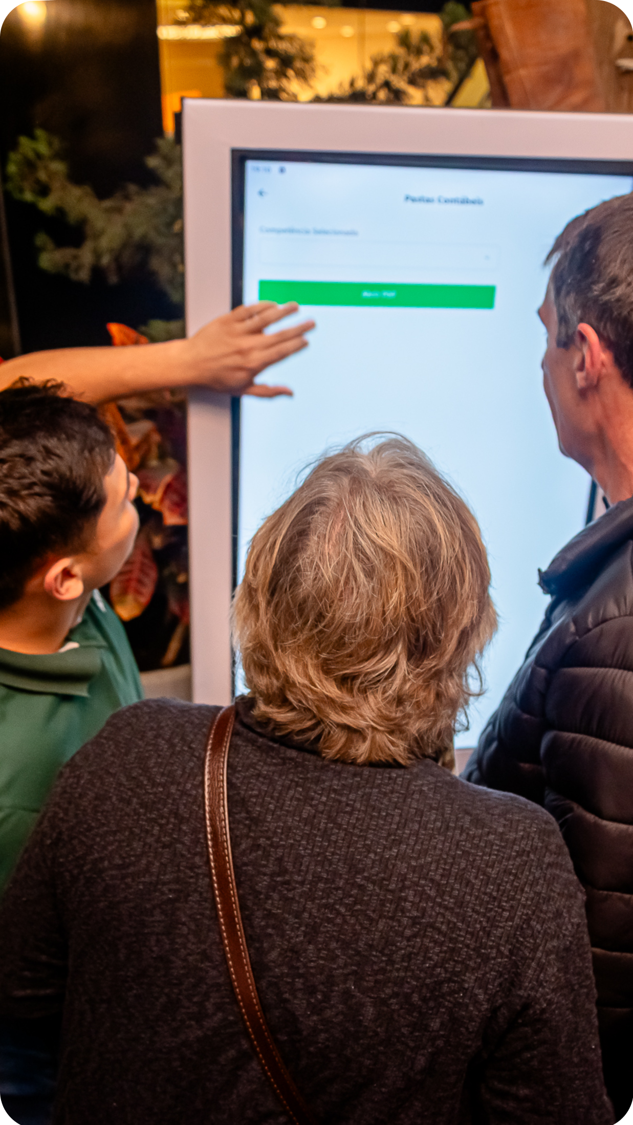 Pessoas utilizando o aplicativo da Aliança em um totem